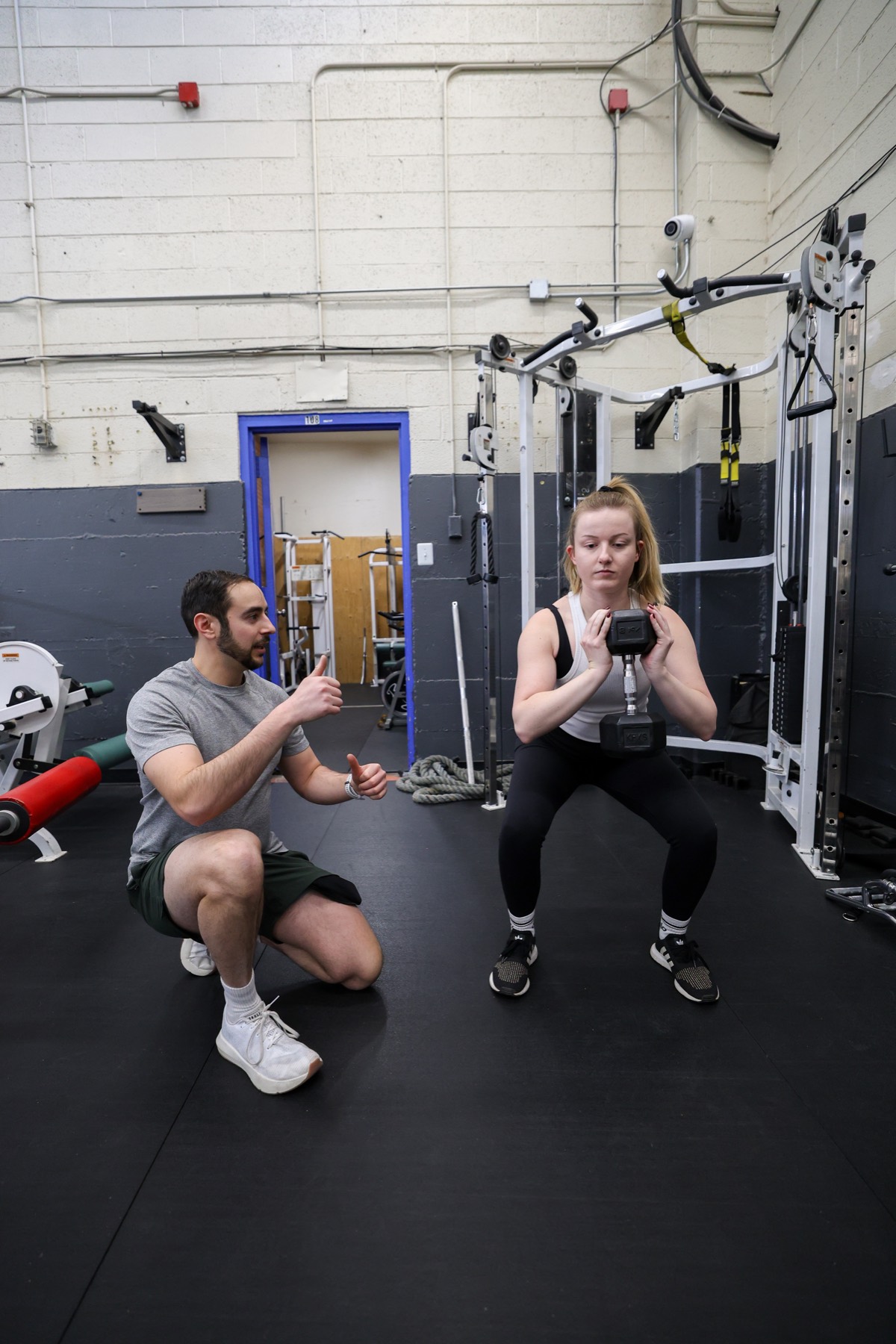 Coach guiding a client through a goblet squat